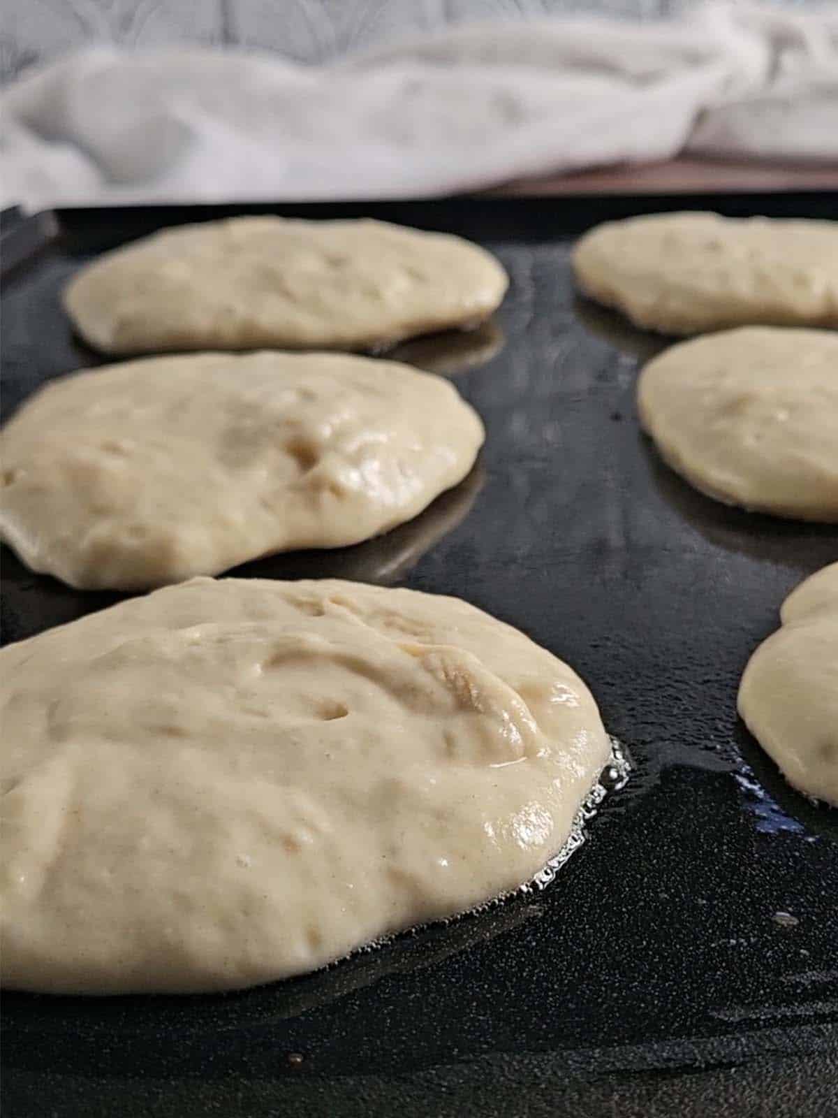 Pancakes cooking on a griddle.