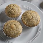 Three lemon poppyseed muffins on a white plate.