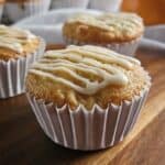 Orange Creamsicle muffin drizzled with icing on top of a wooden board.