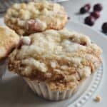 Three cranberry cream cheese muffins on a white plate.