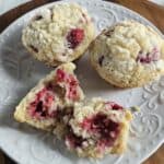 Three raspberry muffins on a white plate.