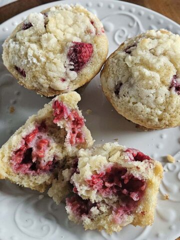 Three raspberry muffins on a white plate.