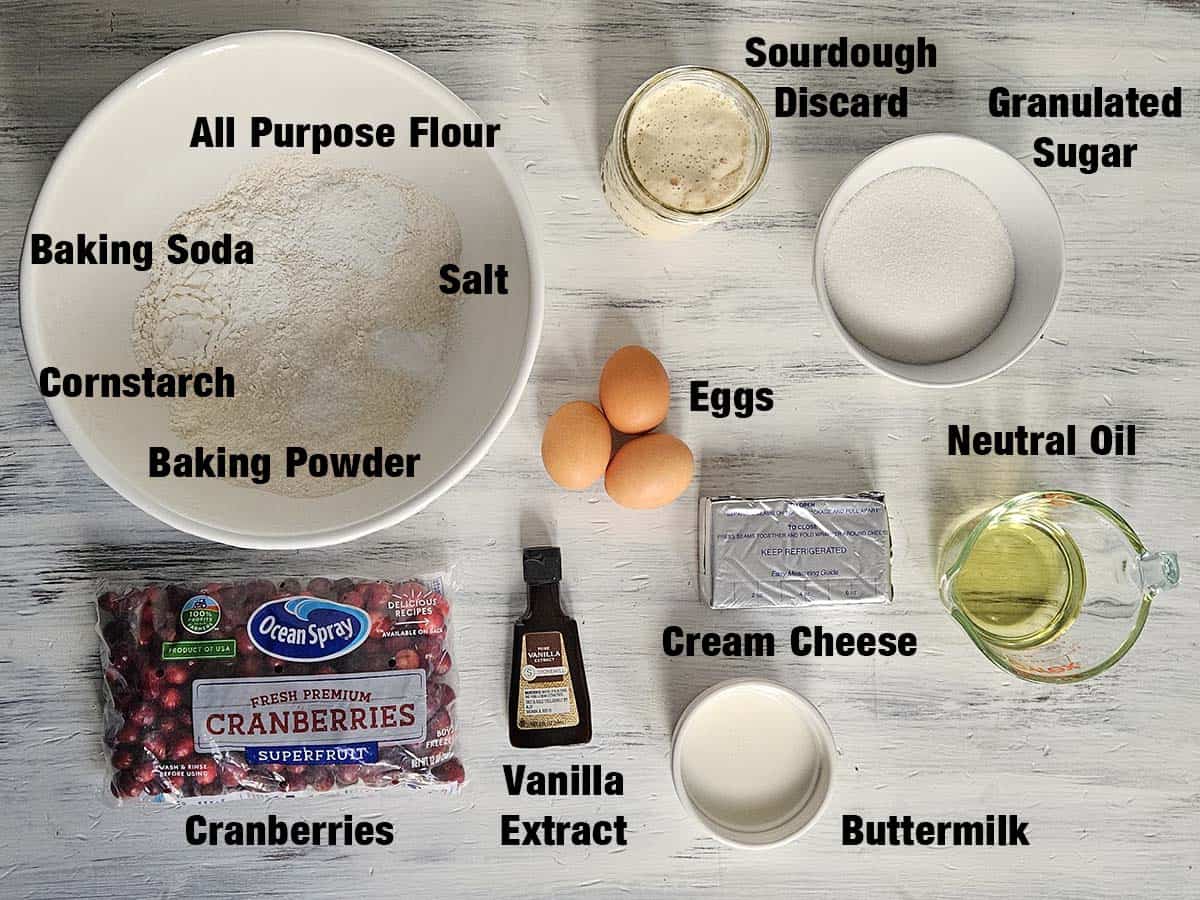 Sourdough cranberry cream cheese muffin ingredients on a white wood surface.
