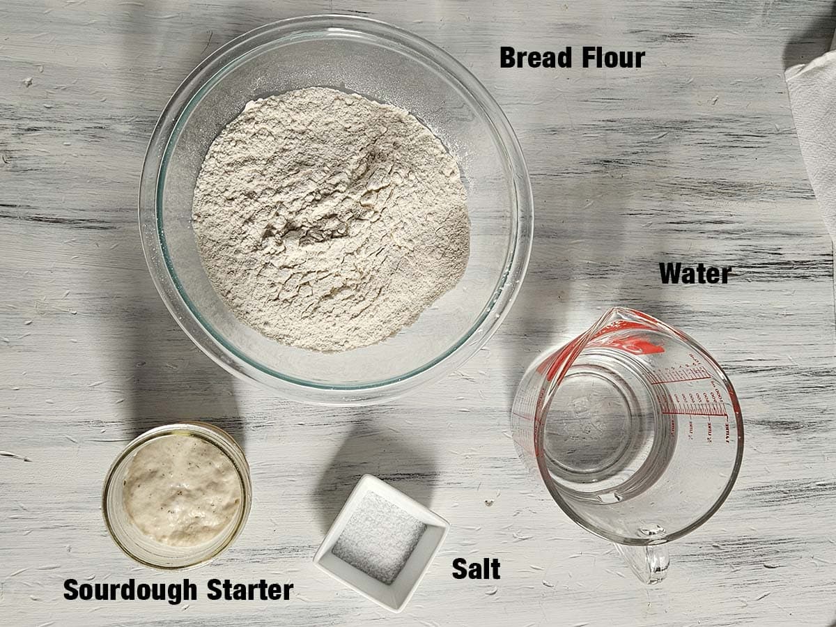 Sourdough bread ingredients on a white wood surface.