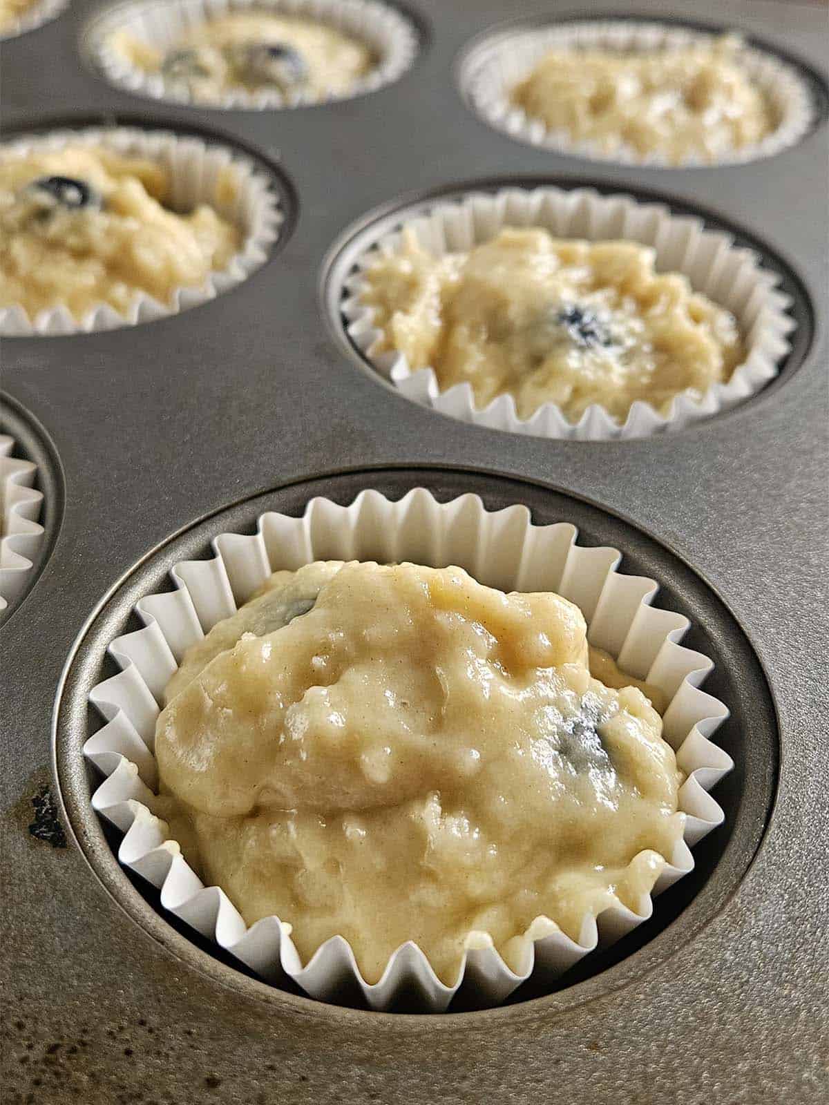 Sourdough blueberry muffin batter in a muffin pan.