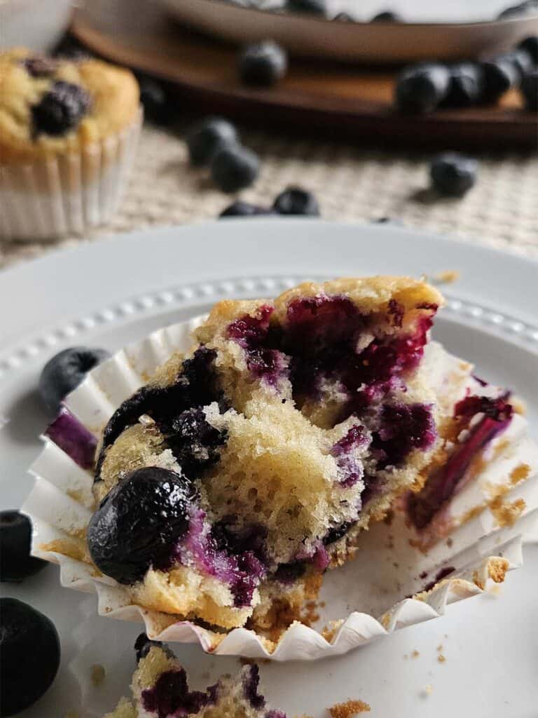 Half a sourdough blueberry muffin on a white plate.